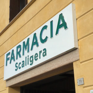 Insegna a cassonetto traforato effetto specchio installata su facciata di farmacia